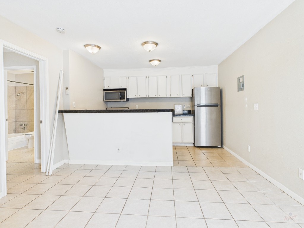 304 East 33rd Street, Unit 10 Austin, TX 78705 - Photo 3 of 28 a kitchen with a refrigerator a microwave and white cabinets