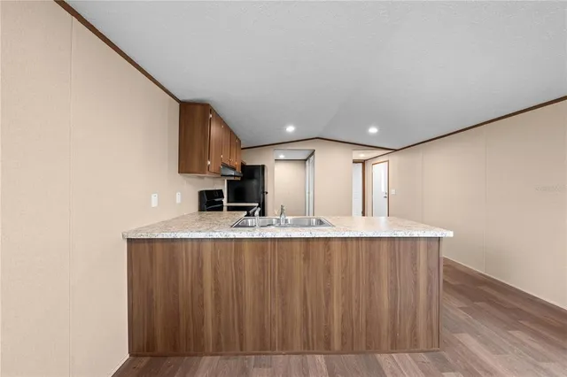 a large kitchen with kitchen island a sink dishwasher a stove and a refrigerator with wooden floor