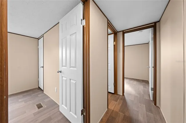 a view of a hallway with wooden floor and a bathroom