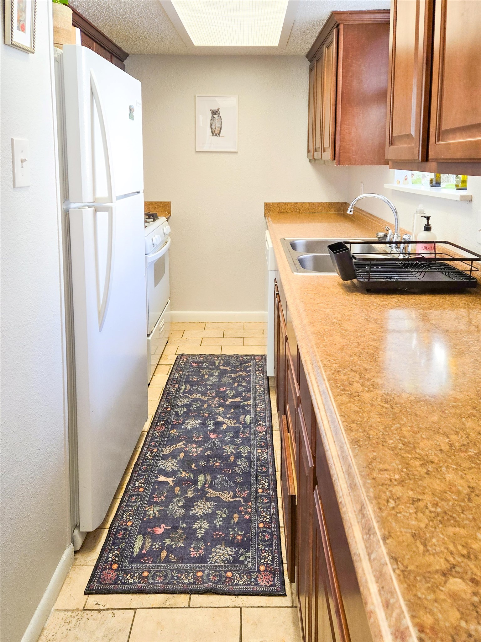 1725 Toomey Road, Unit 102 Austin, TX 78704 - Photo 8 of 13 Kitchen with white appliances, light tile patterned floors, and wood finish cabinets