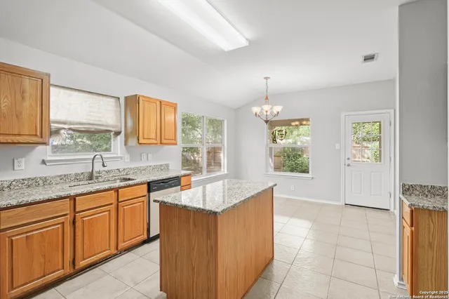 a large kitchen with granite countertop a sink window and cabinets