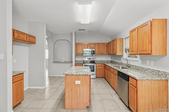 a large kitchen with stainless steel appliances granite countertop a stove a sink dishwasher and a refrigerator