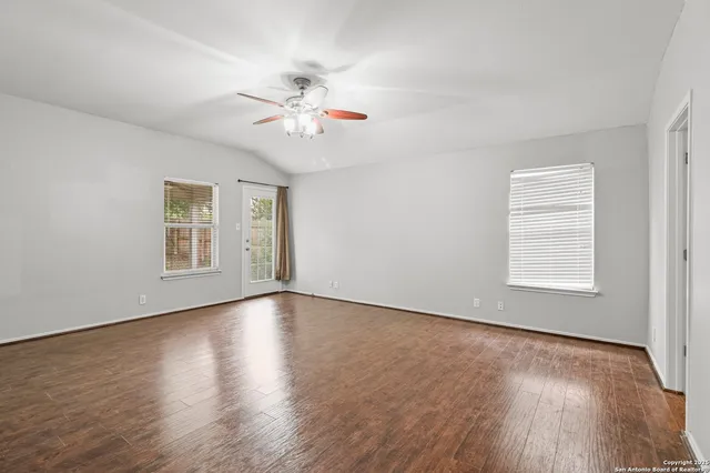 a view of an empty room with a window and wooden floor