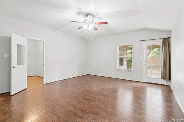 an empty room with wooden floor chandelier and windows