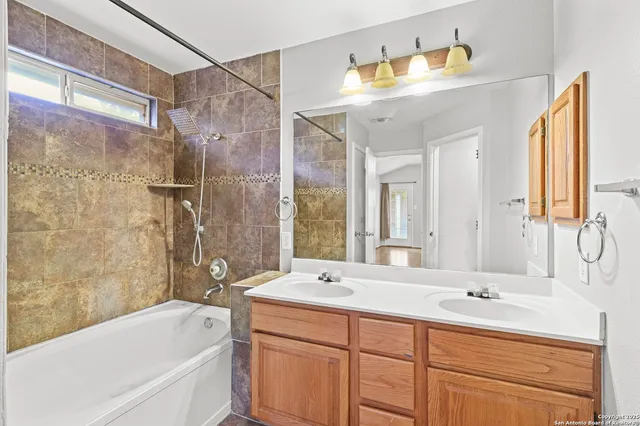 a bathroom with a double vanity sink mirror and bathtub