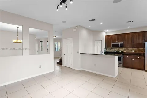 a kitchen with stainless steel appliances kitchen island granite countertop a refrigerator and a sink
