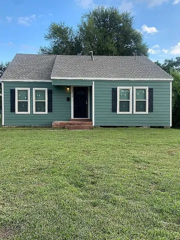 a front view of house with yard and trees around