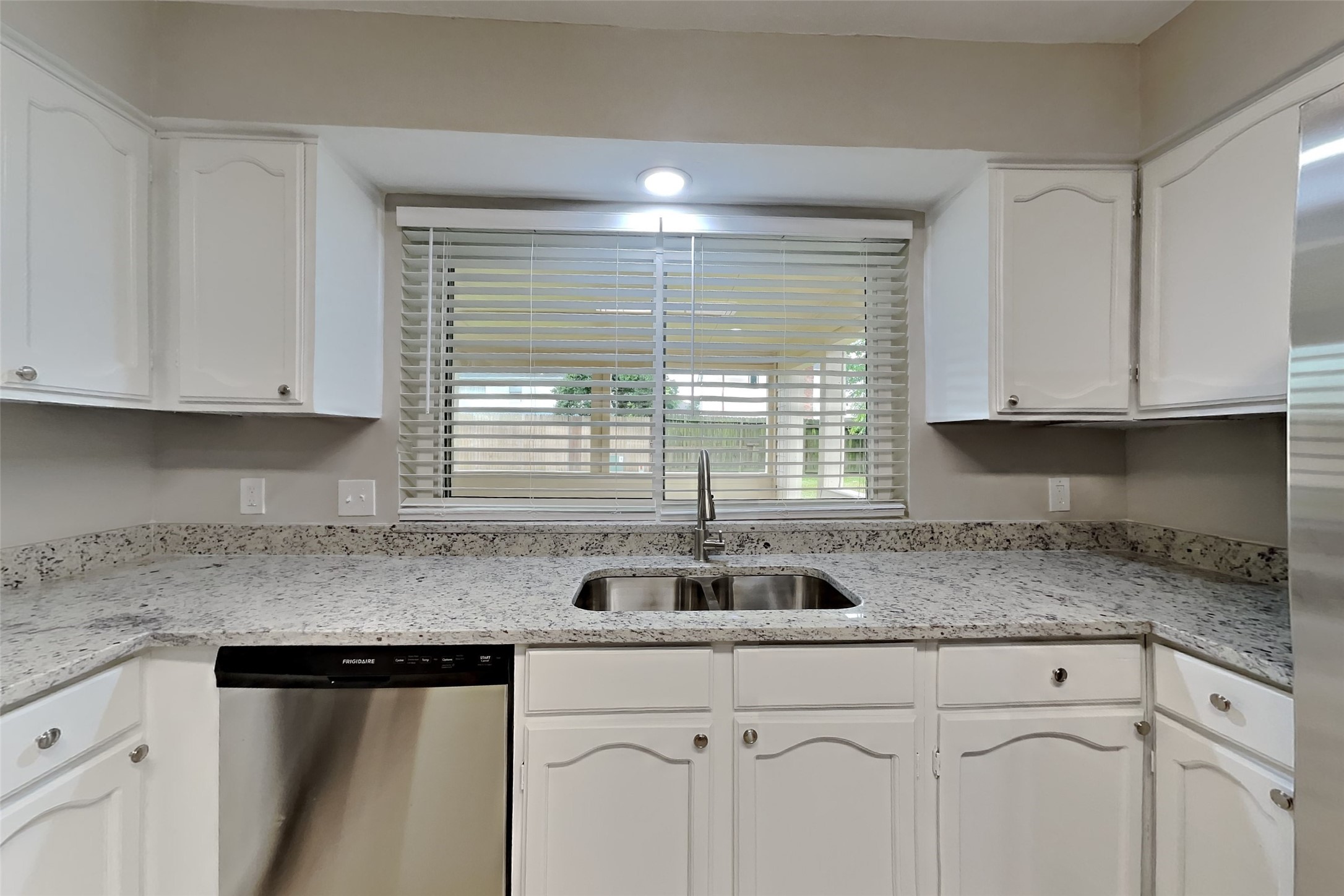 10015 Rippling Fields Drive Houston, TX 77064 - Photo 6 of 24 a kitchen with granite countertop white cabinets sink and window