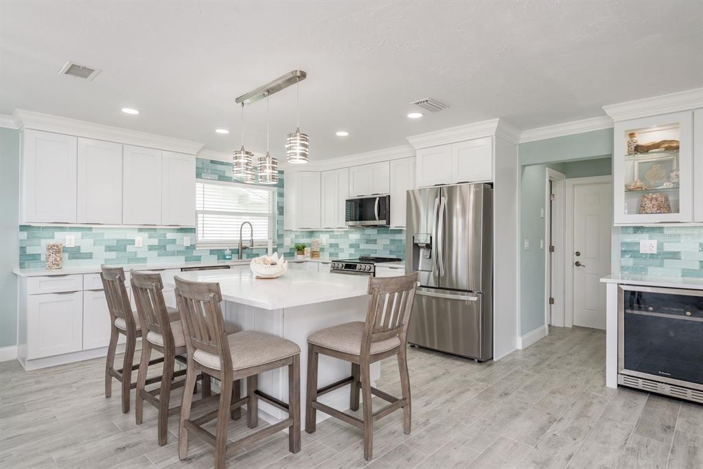 3301 Seaway Drive New Port Richey, FL 34652 - Photo 13 of 53 a kitchen with refrigerator cabinets dining table and chairs