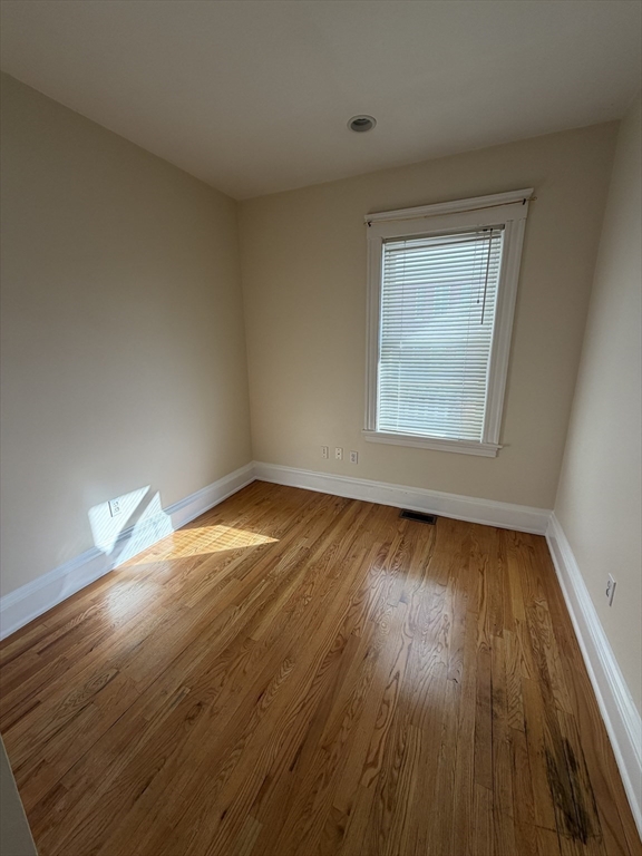 555 Heath Street, Unit 1 Brookline, MA 02467 - Photo 3 of 7 an empty room with wooden floor and windows