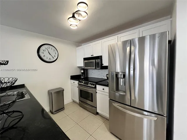 a kitchen with stainless steel appliances granite countertop a refrigerator a stove and a sink with wooden floor