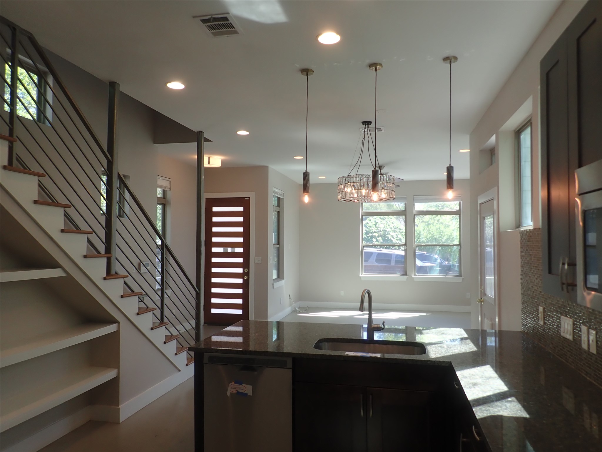 2912 East 14th Street, Unit A Austin, TX 78702 - Photo 12 of 27 Kitchen featuring dark stone countertops, stainless steel appliances, a peninsula, hanging light fixtures, and built in shelves