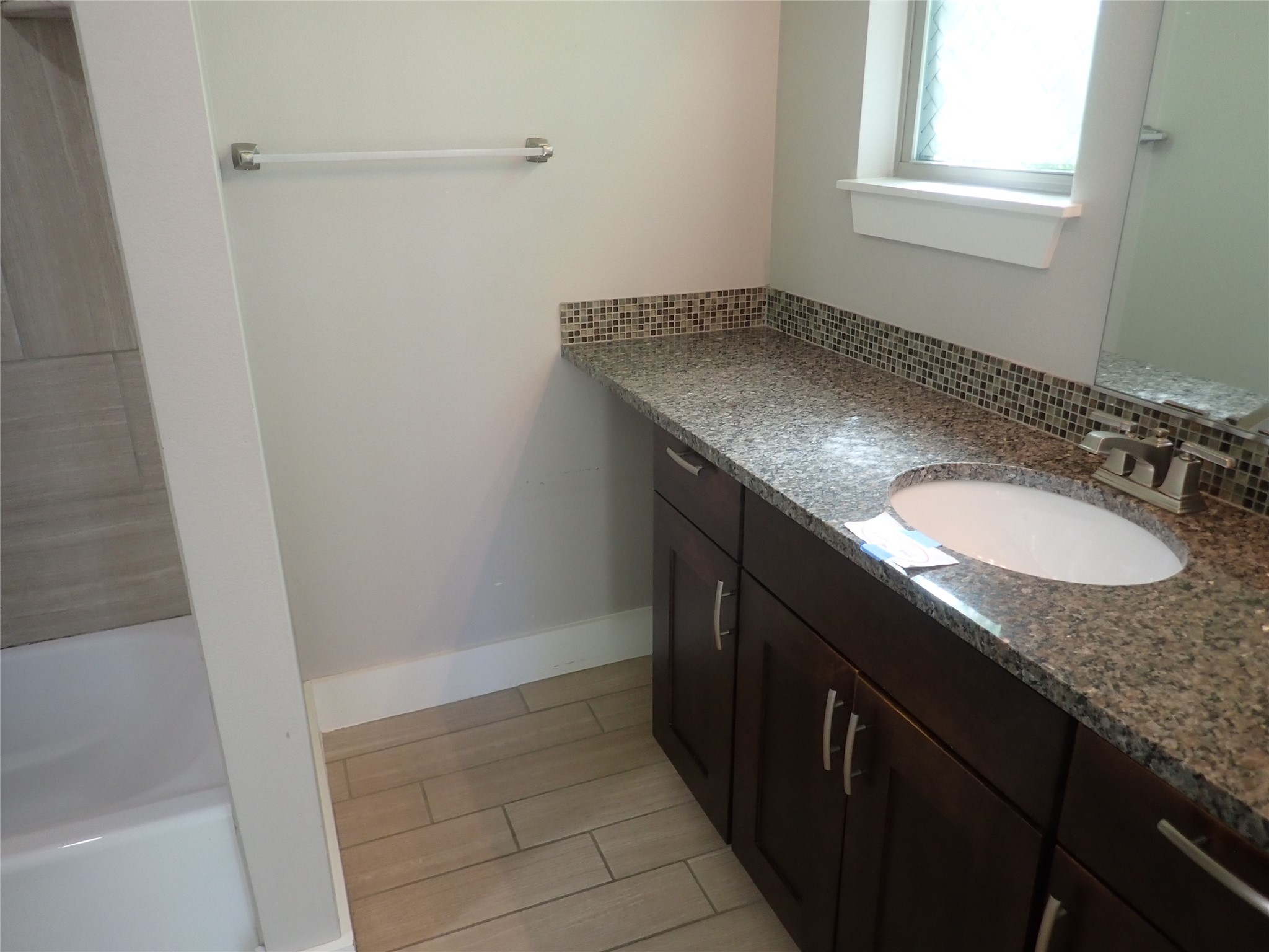 2912 East 14th Street, Unit A Austin, TX 78702 - Photo 16 of 27 Primary Bathroom featuring vanity, backsplash, and wood tiled floors