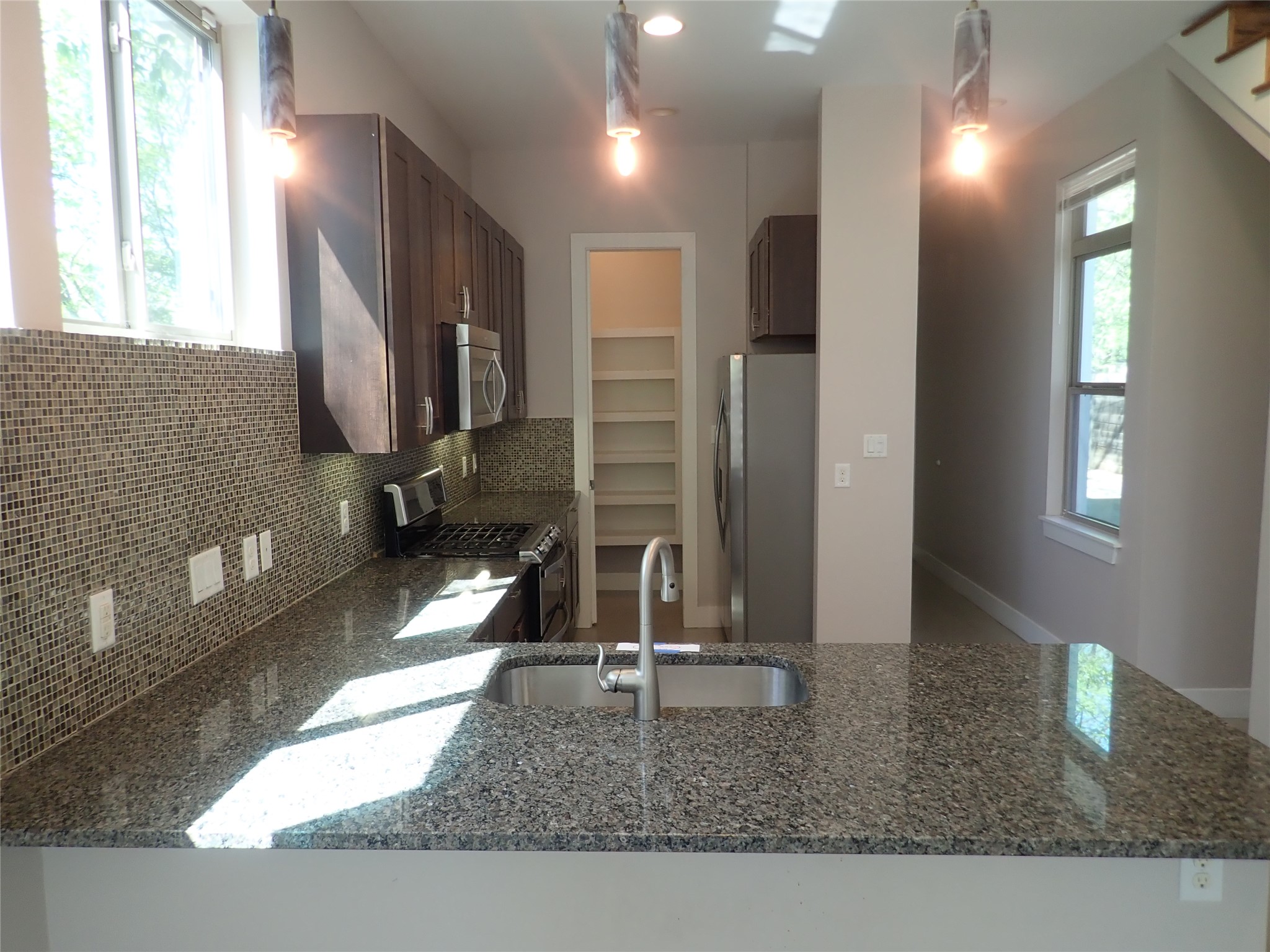 2912 East 14th Street, Unit A Austin, TX 78702 - Photo 10 of 27 Kitchen with dark stone counters, stainless steel appliances, plenty of natural light, and dark wood finish cabinets
