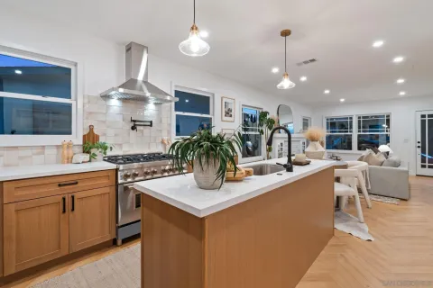 a view of a kitchen with kitchen island stainless steel appliances a sink and living room view