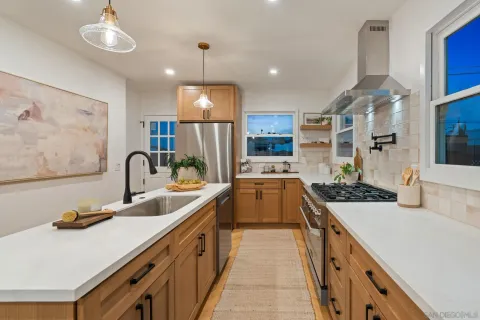 a large kitchen with stainless steel appliances a large counter top a stove a chimney a sink and a refrigerator