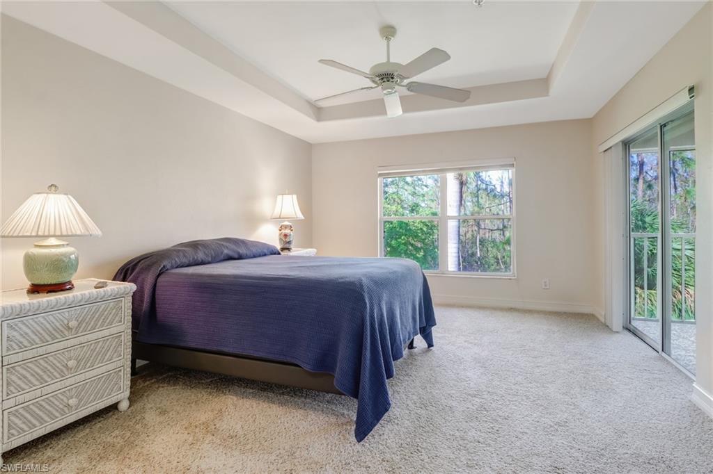 849 Carrick Bend Circle, Unit 202 Naples, FL 34110 - Photo 11 of 20 a spacious bedroom with a bed chandelier and a window