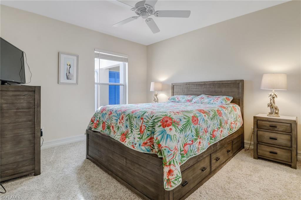 849 Carrick Bend Circle, Unit 202 Naples, FL 34110 - Photo 15 of 20 a bedroom with a bed and a chandelier