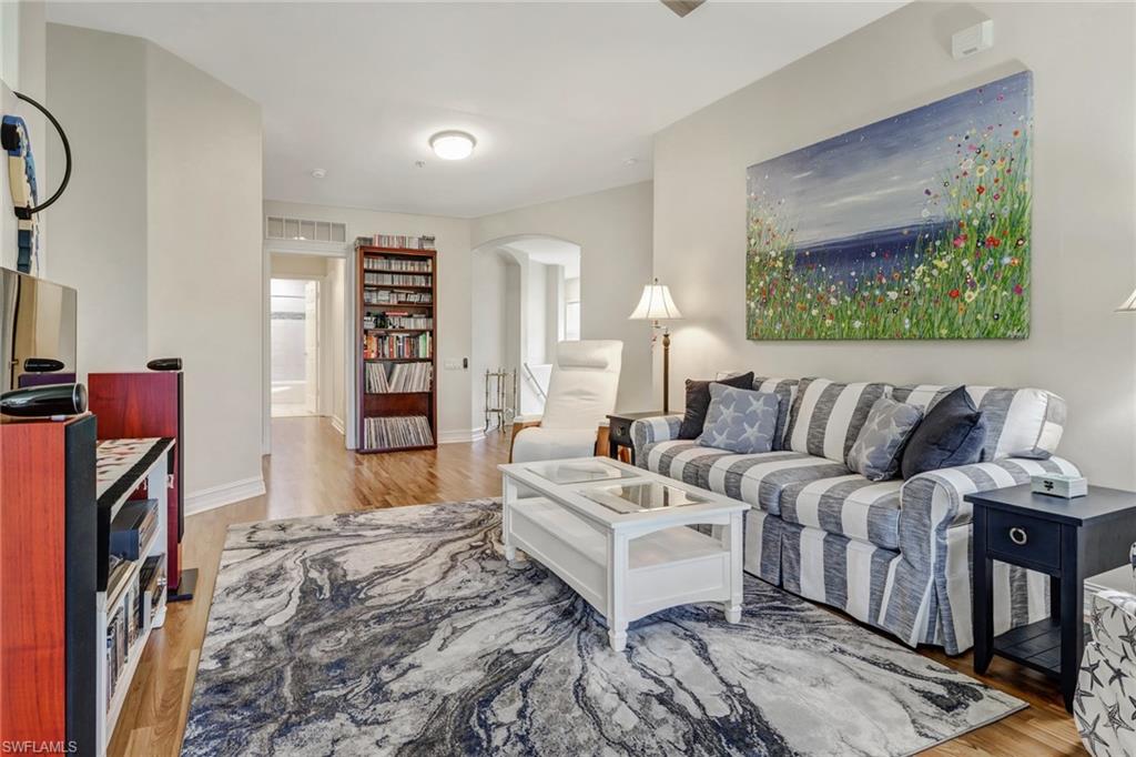 849 Carrick Bend Circle, Unit 202 Naples, FL 34110 - Photo 2 of 20 a spacious bedroom with a bed a couch and a painting on the wall