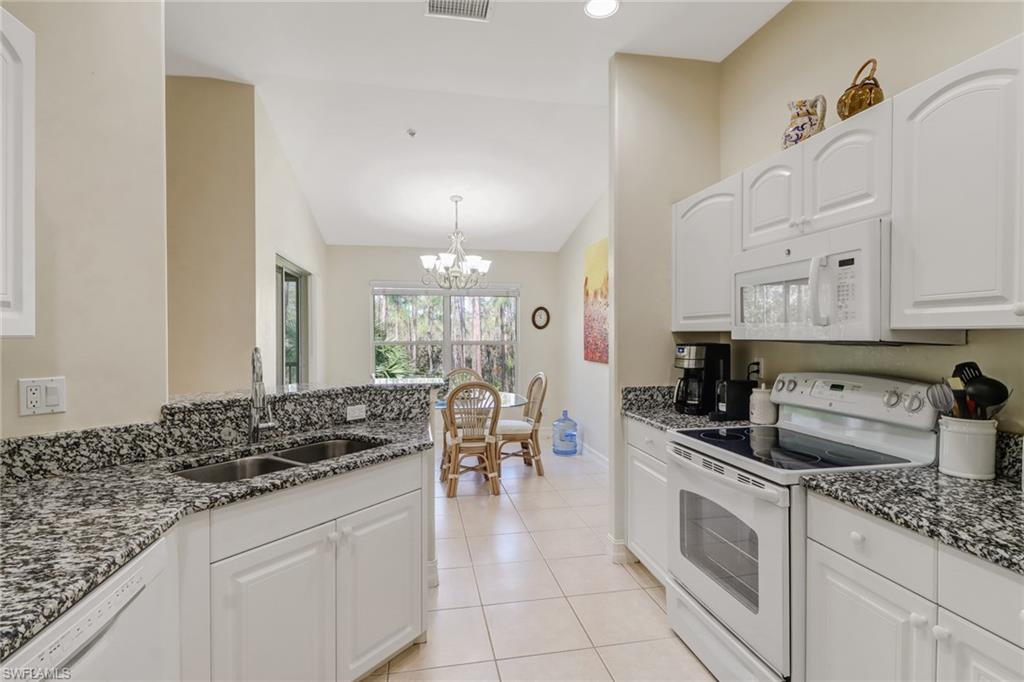 849 Carrick Bend Circle, Unit 202 Naples, FL 34110 - Photo 7 of 20 a kitchen with white cabinets and appliances