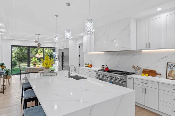a kitchen with a sink a stove and white cabinets