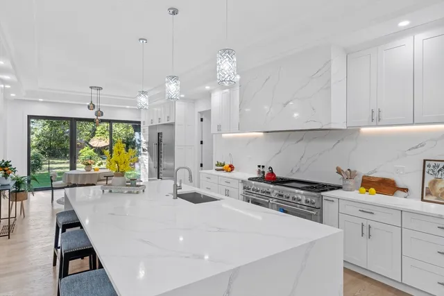 a kitchen with a sink a stove and white cabinets