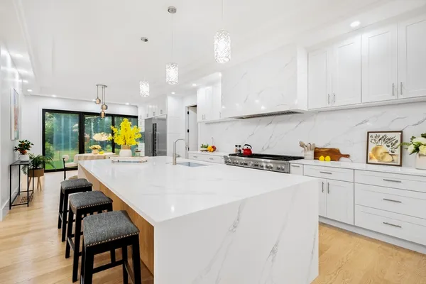 a kitchen with stainless steel appliances kitchen island a table chairs refrigerator and sink