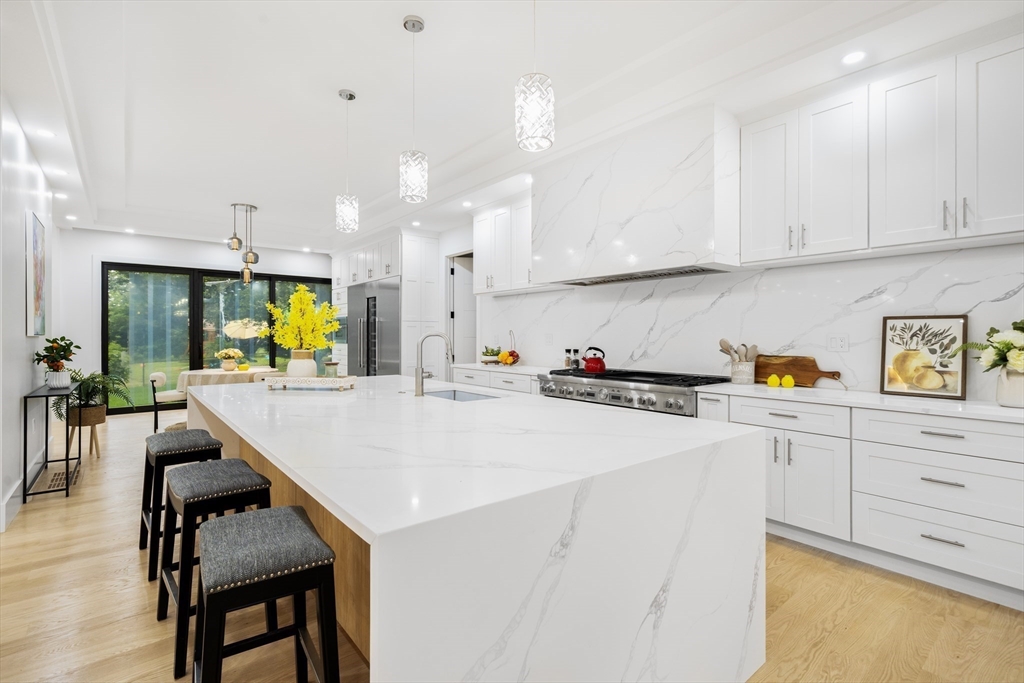 197 Woburn Street Lexington, MA 02420 - Photo 9 of 42 a kitchen with stainless steel appliances kitchen island a table chairs refrigerator and sink