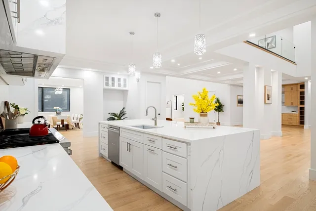 a large white kitchen with a large counter space and wooden floor