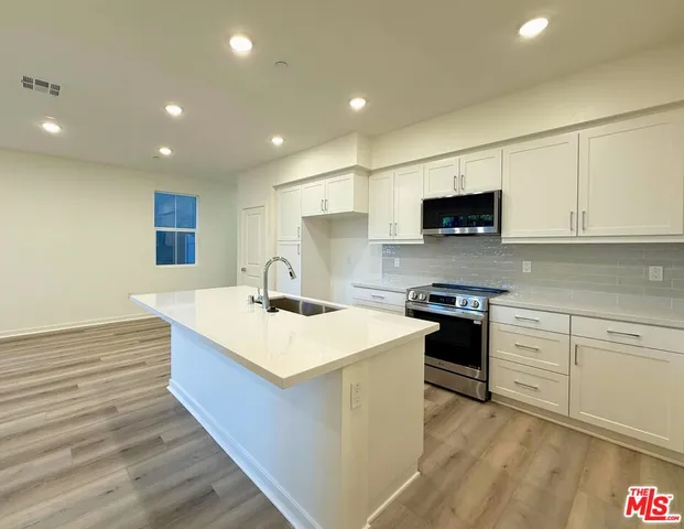 a large kitchen with stainless steel appliances granite countertop a stove a sink and a microwave