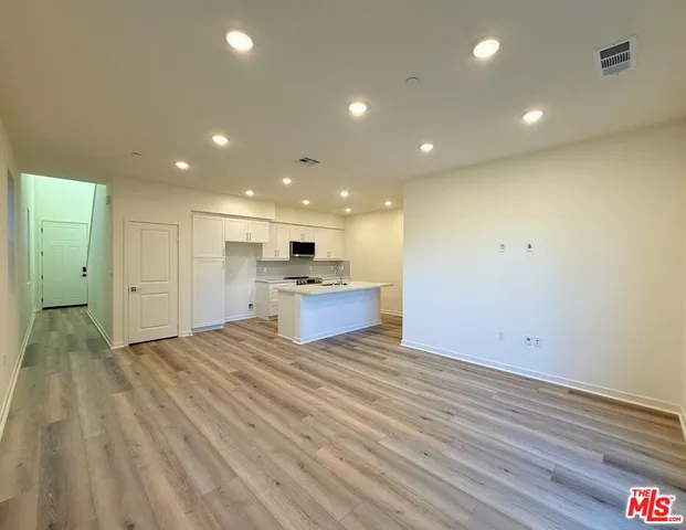 a view of kitchen with kitchen island wooden floor center island and stainless steel appliances