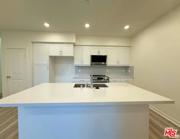 a kitchen with a appliances a sink and a stove top oven with wooden floor