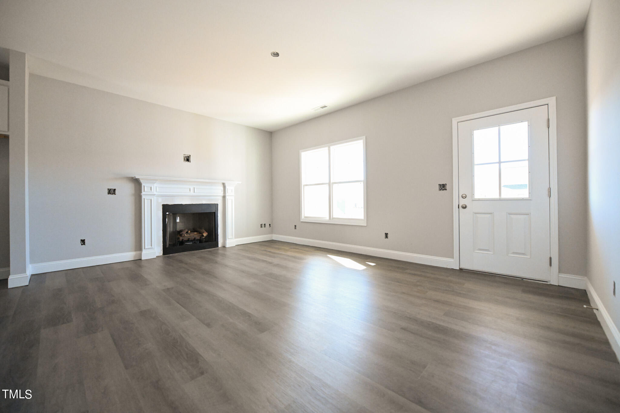 150 Johnson Ridge Way Four Oaks, NC 27524 - Photo 3 of 24 an empty room with wooden floor fireplace and windows