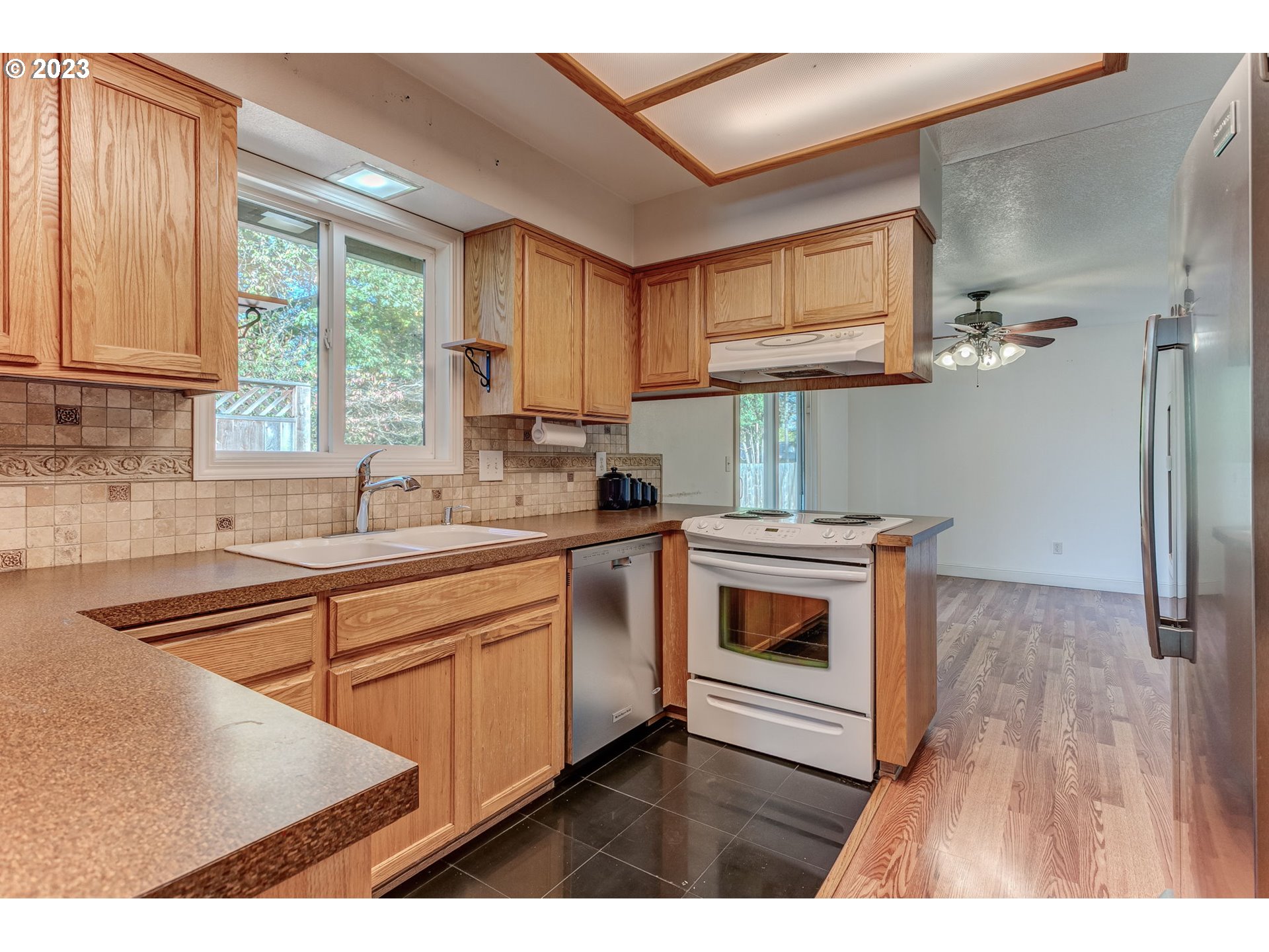 21321 Southeast Alder Street Gresham, OR 97030 - Photo 6 of 39 a kitchen with stainless steel appliances granite countertop a stove a sink dishwasher and a microwave oven with wooden cabinets
