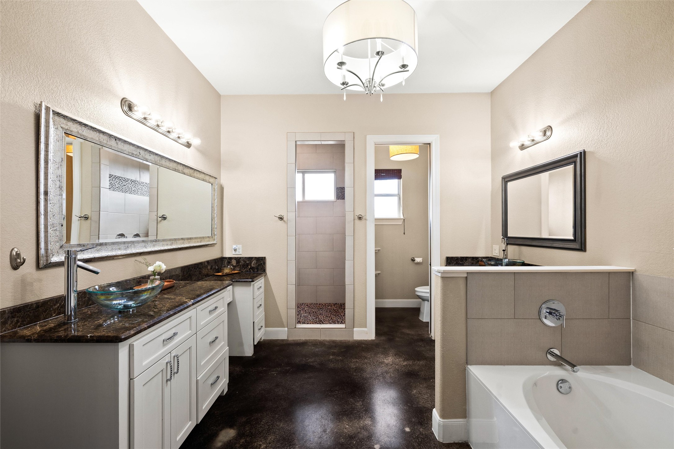 106 Fallow Way Bastrop, TX 78602 - Photo 21 of 40 Primary bathroom featuring two vanities, walk in shower, concrete floors, and a chandelier