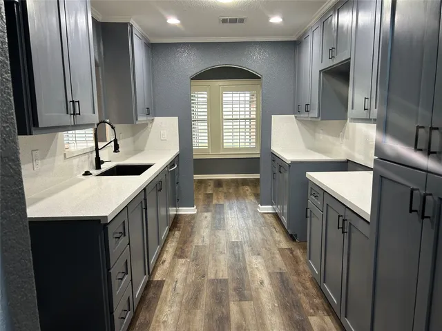 a kitchen with granite countertop a sink a counter space and cabinets