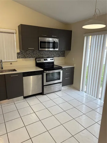 a kitchen with stainless steel appliances granite countertop a refrigerator and a stove top oven