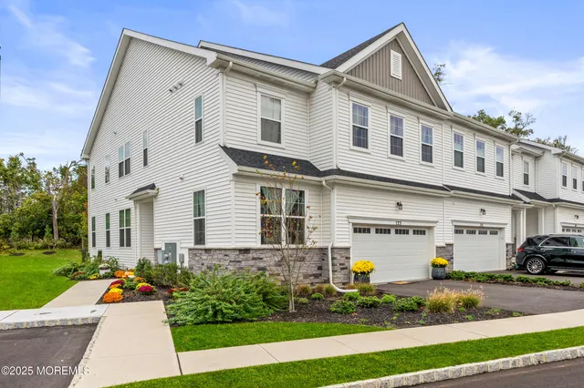 a view of a white house with outdoor seating next to a yard