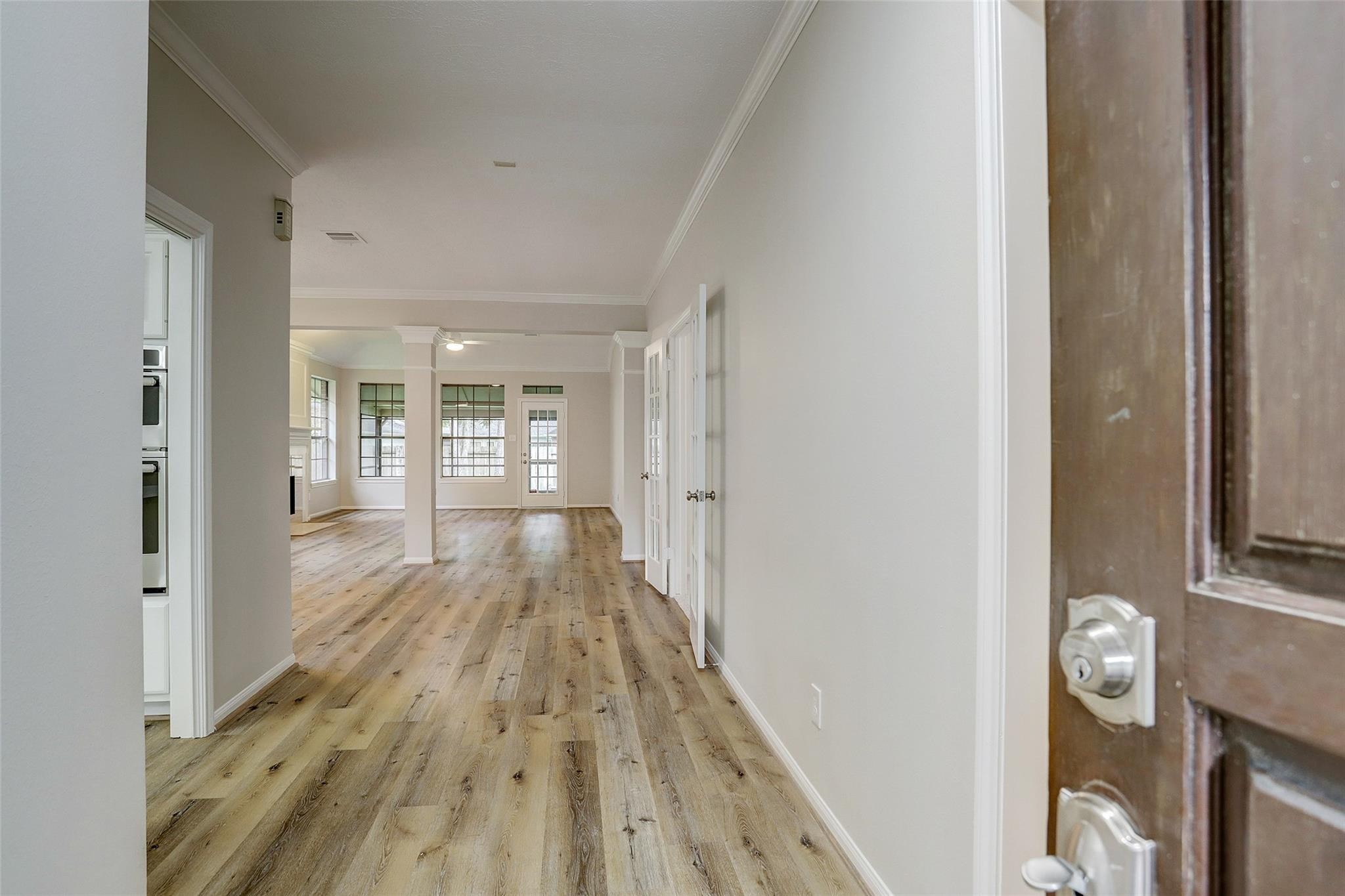 10 Heathstone Place The Woodlands, TX 77381 - Photo 21 of 27 Step into a bright, open-concept living area featuring beautiful wood flooring and large windows, all enhanced by neutral wall colors for a modern, inviting atmosphere.