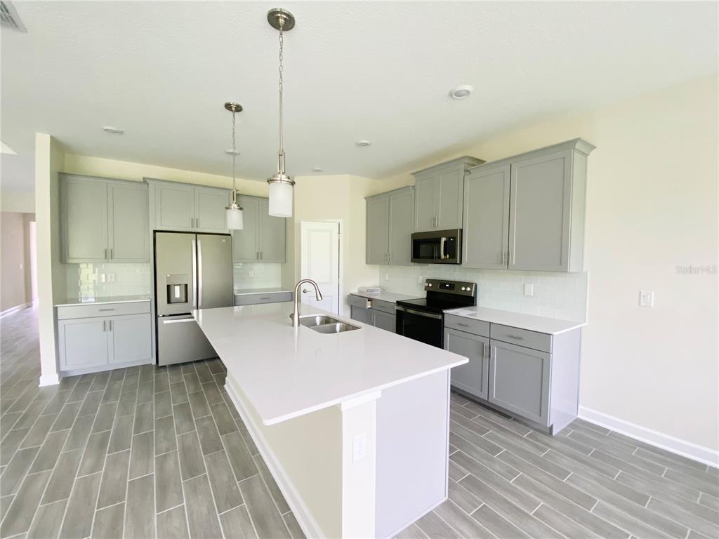 2768 Norway Maple Court Ocoee, FL 34761 - Photo 5 of 35 a large white kitchen with sink a refrigerator and white cabinets
