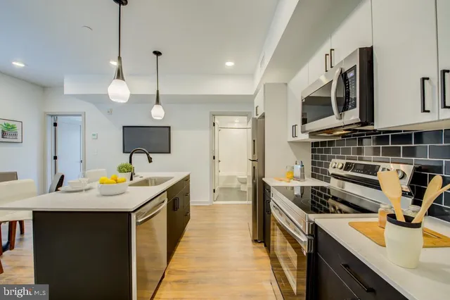 a kitchen with kitchen island a sink a counter space appliances and cabinets