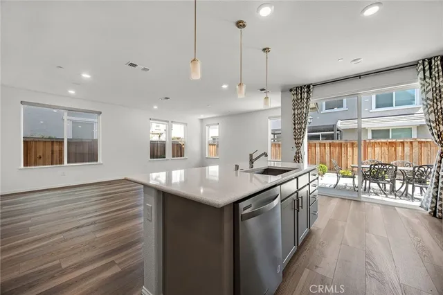 a kitchen with stainless steel appliances granite countertop a sink a stove and a wooden floor