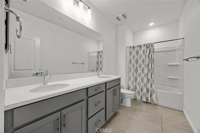 a spacious bathroom with double sink a toilet a shower and a mirror