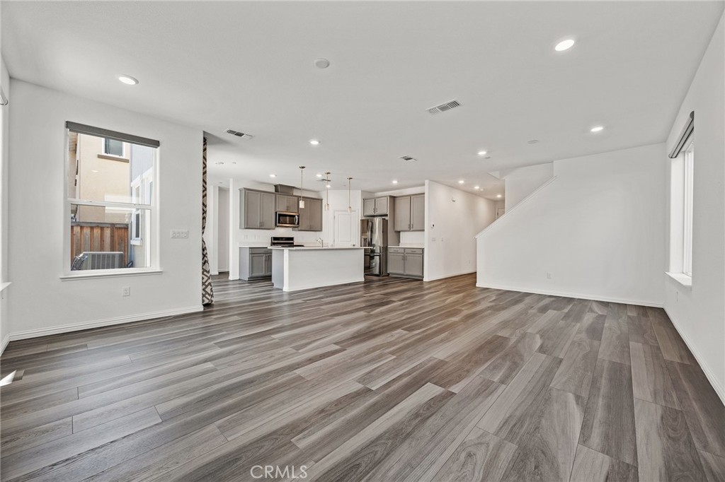 237 Goose Creek Avenue Brentwood, CA 94513 - Photo 4 of 49 a view of an empty room with wooden floor and a kitchen