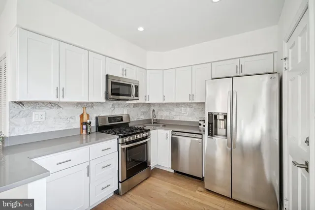 a kitchen with white cabinets and stainless steel appliances