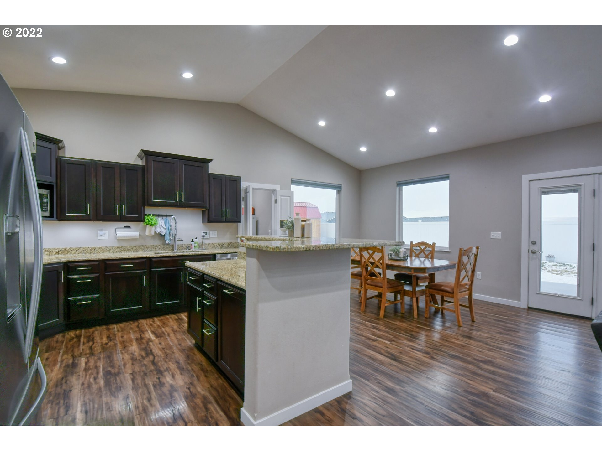 1803 Southwest 3rd Street Pendleton, OR 97801 - Photo 15 of 32 a kitchen with stainless steel appliances granite countertop a refrigerator a stove top oven a sink dishwasher a dining table and chairs with wooden floor
