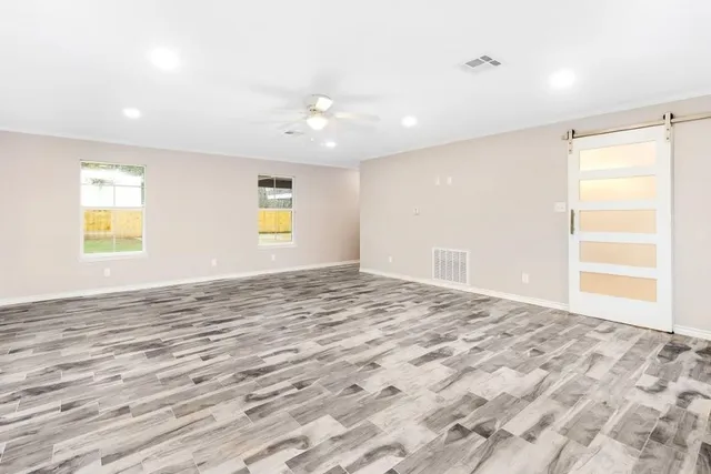 a view of empty room with wooden floor and fan