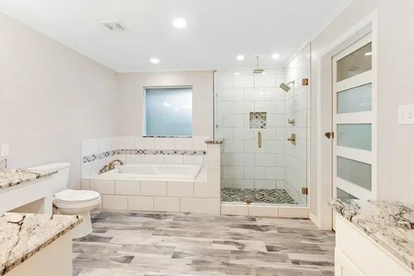 a bathroom with a granite countertop sink a toilet a mirror and shower
