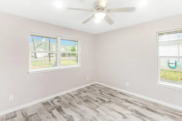 a view of empty room with window and wooden floor