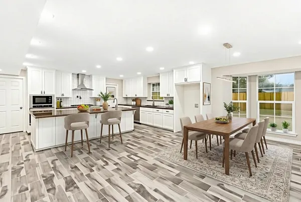 a living room with stainless steel appliances kitchen island granite countertop a dining table chairs and a refrigerator